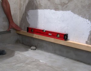 Set and fix the bar on the wall for laying the first row of tiles